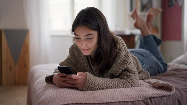 Young teenage girl srolling her smartphone in the room.