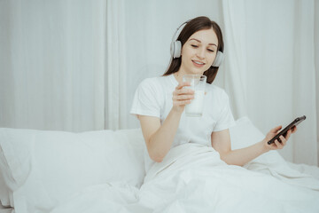 Happy woman holding apple and listening to music sitting on sofa in living room at home