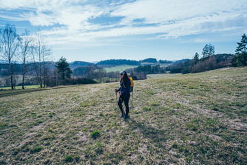 Fototapeta na wymiar Woman with backpack hiking in remote sunny rural field.