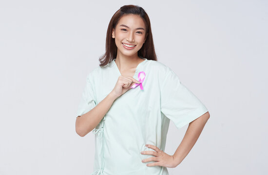 Happy smile asian woman patient showing pink badge ribbon chest to support breast cancer cause campaign. breast cancer awareness concept. - Powered by Adobe