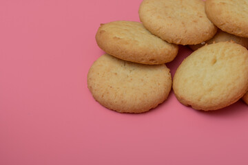 Okrągłe maślane słodkie ciastka na różowym stoliku