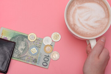 Filiżanka z kawą obok portfela i polskich pieniędzy na różowym tle