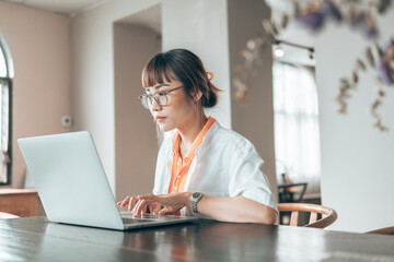Woman wear eyeglasses and using laptop computer. woman looking and working with laptop.