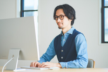 パソコンに向かってタイピングをする若い男性