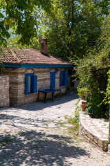 Fototapeta na wymiar old stone village house with blue wooden windows on the farm