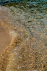 Background, wallpaper. Texture of sea sand through a layer of water with sun glare on the waves