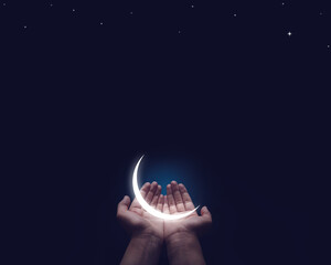 A Half-illuminated moon in hand. Ramadan and Eid Greetings concept. Muslim Holidays and Eid-Ul-Adha...
