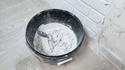 white putty cement in black bucket on floor for rebuild wall at home 