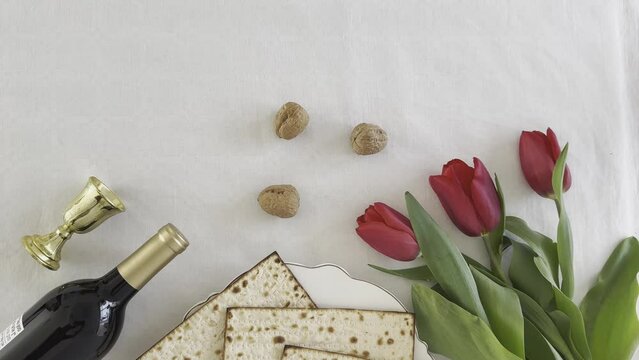 Matzah shape of heart with red tulips, bottle of wine and walnut on white background. Traditional Holiday on Passover. Home symbol of lovely Jewish family in pesach. top view