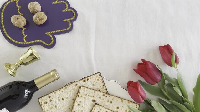 Matzah shape of heart with red tulips, bottle of wine and walnut on white background. Traditional Holiday on Passover. Home symbol of lovely Jewish family in pesach. top view