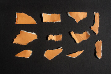 Set of wrinkled orange paper pieces on a black background. Ripped paper.