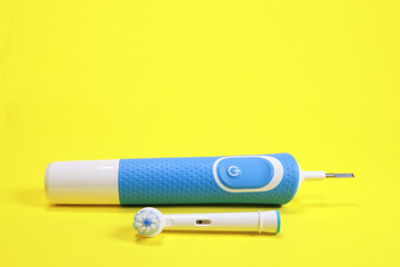 electric toothbrush and toothbrush head on yellow background, concept of oral hygiene, dental care