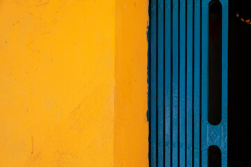 Yellow and blue abstract background divided in two halves vertically. Brightly colored wall and folding gate of a Vietnamese house