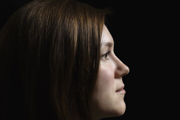 Side portrait of a model on a black background. Black and white portrait of a woman from the side.