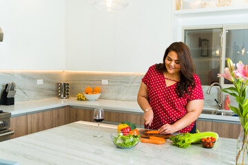 Happy fat woman preparing food and cooking dinner in the kitchen