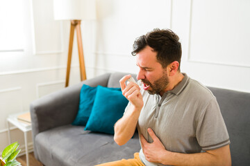 Ill man suffering from asthma using an inhaler