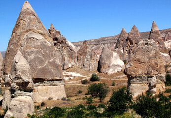 Landscape with mushroom-shaped mountains (also called Fairy Chimneys) in the Rose Valley between the towns of Goreme and Cavusin in Cappadocia, Turkey