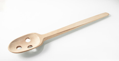 Wooden kitchen utensils. Large wooden spoon with holes for stirring cooked food