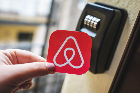 Airbnb logo next to a smart key lock box. Contactless check-in to the holiday apartment, short term accommodation bookings for tourists. Budapest, Hungary - February 3, 2023.
