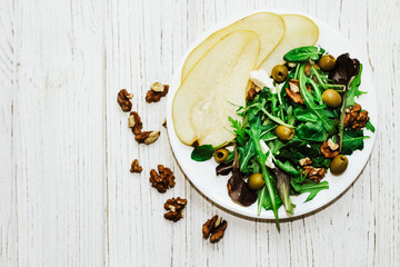 Salad with pears, herbs, arugula, prosciutto, cheese, green olives and nuts.