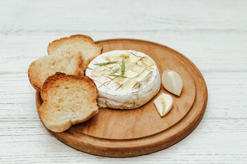 White baguette cut into pieces with olive oil and Camembert cheese on the table.