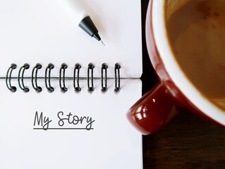 blur coffee and notebook with text written MY STORY, concept of first time book writing, author...