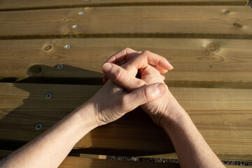 meine Hände und Finger, die auf dem Holztisch gekreuzt sind, während ich mich von einem Spaziergang in der Natur ausruhe
