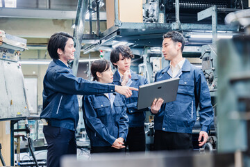 タブレット端末を見ながら会議をする工場スタッフ