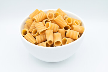 Whole wheat mezze Rigatoni pasta, in a white bowl, isolated on a white background