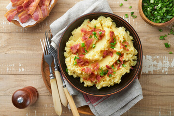 Mashed potatoes. Bacon mashed potatoes with green onion, pepper and cheddar cheese in bowl on old wooden backgrounds. Delicious creamy mashed potatoes. Top view.