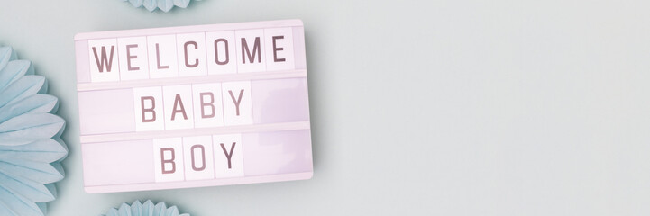Welcome baby boy. Baby shower concept. Banner with lightbox with letters and tissue paper fans in a blue color.
