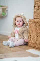 Fashionable cute baby toddler  in a plush jacket at home