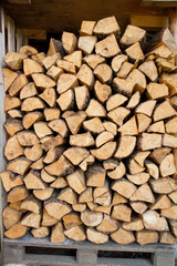 Pile of firewood in the summer stocked outdoors in a shed, being prepared for winter