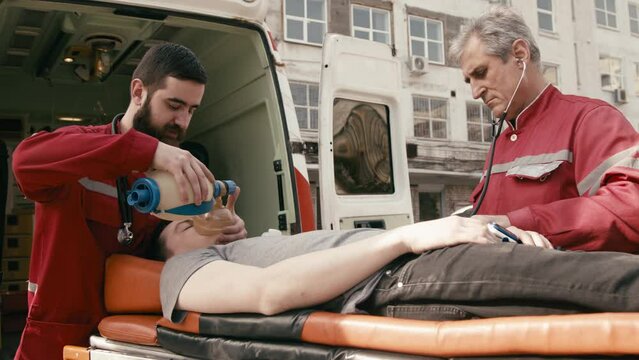 life saving concept. A professional paramedic uses a laptop to complete an injured patient's questionnaire on the way to the hospital. A paramedic works in an ambulance