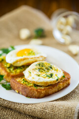 Fried croutons in batter with garlic and herbs and a fried egg in a plate.