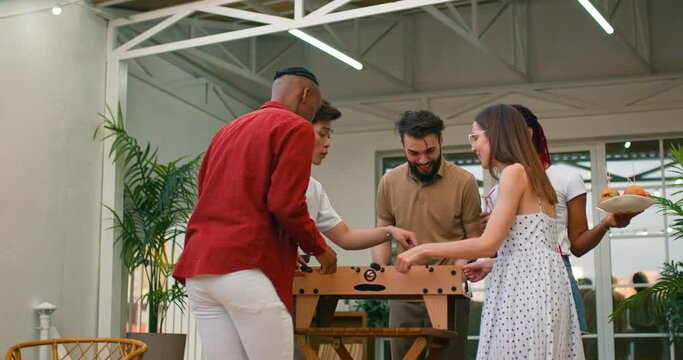 woman, team winning game at foosball table, do fun activity after work. Multi ethnic people enjoying football play celebrating with snacks Slow motion girl clapping hands,applauding,jumping happiness