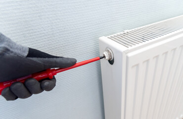 Handyman venting a radiator or heater to let the air escape