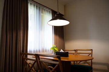 Dark home interior with wood dining table lit by lamp, evening light for dinner.