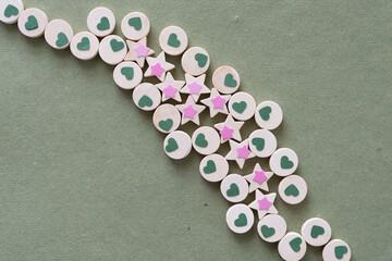 small paper hearts and stars on wooden objects (circles and stars) on rough green paper