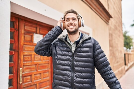 Young man smiling confident listening to music at street