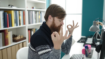 Young redhead man student doing yoga exercise relaxing at library university