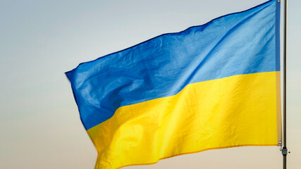 Close-up National flag of Ukraine waving against the wind in the sky of sunrise or sunset outdoors background. Concept of Peace, Ukraine flag. Freedom, Symbol, Independence Day, Pray for Ukraine