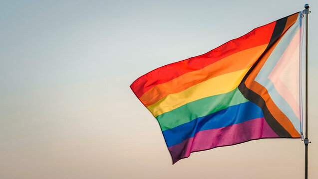 LGBT History Month, Pride Month, LGBT Lesbian, Gay, Bisexual, Transgender, Queer or Questioning, Parade Concept. Six-band Rainbow flag waving in wind,  outdoor background, soft focus. Slow motion