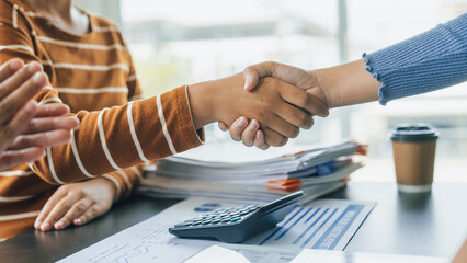 Shaking hands, Close up group of business woman discussion and brainstorming, bookkeeping audit graph and chart documents at desk, teamwork concept.
