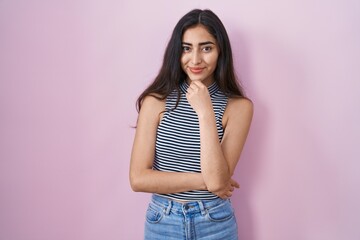 Young teenager girl wearing casual striped t shirt looking confident at the camera smiling with crossed arms and hand raised on chin. thinking positive.