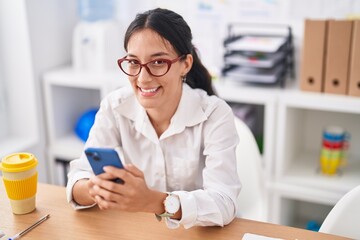 Young beautiful hispanic woman business worker using smartphone working at office