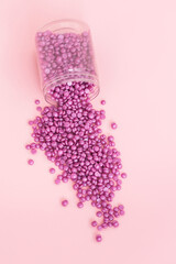 Wax for depilation of violet or purple color on pink background. Concept of waxing, smooth skin, bodycare, spa salon industry.