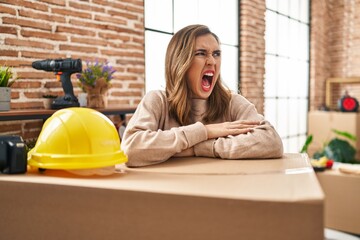 Young woman moving to a new home angry and mad screaming frustrated and furious, shouting with anger. rage and aggressive concept.