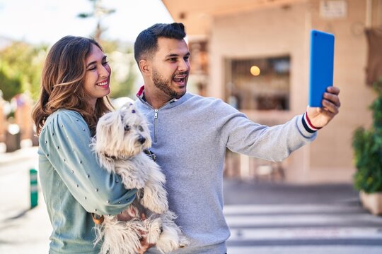 Man and woman holding dog making selfie by the touchpad at street