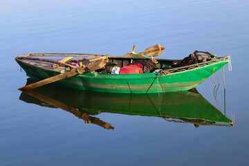 small traditional fishing boat with reflection on water in Upper Egypt